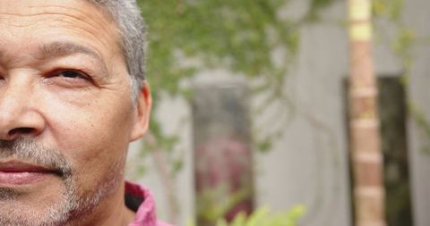 Senior man in pink collared shirt standing in tranquil courtyard