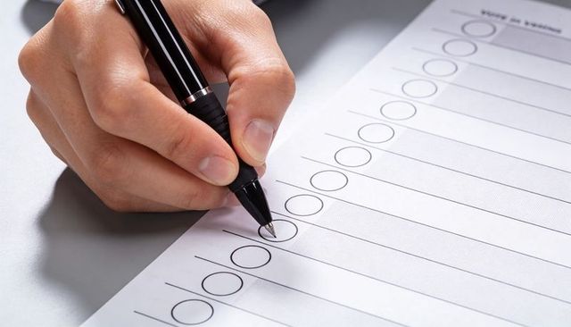 Marking Checklist Circle with Black Pen Closeup on Minimalist Desk for Task Planning