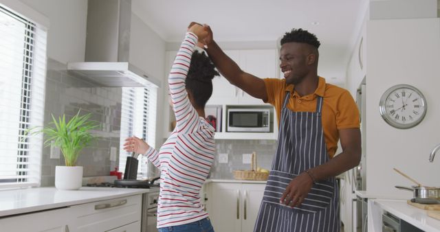 Image of happy african american couple dancing in kitchen. love, relationship, togetherness and spending quality time at home.
