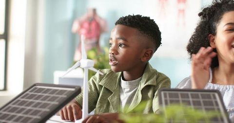 African american boy exploring renewable energy with solar panels and wind turbine