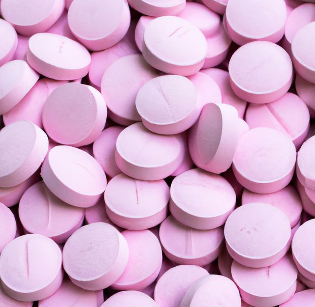 Close up of multiple round pink pills on black background. Medicine, healthcare and treatment concept.