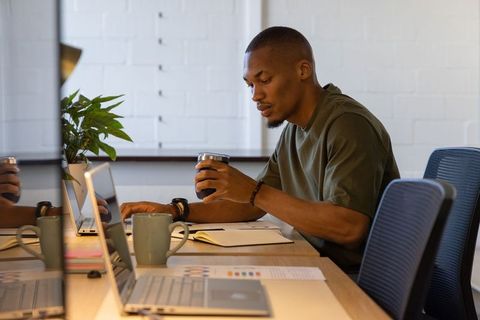 African american professional working in coworking space holding mug and taking notes