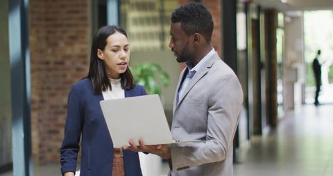 Business Professionals Collaborating with Laptop in Office Hallway