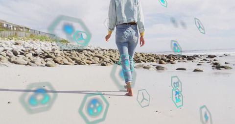 Woman in denim walking on beach with digital technology overlay