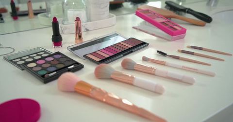 Rose gold makeup brushes and vibrant eyeshadow palettes on white vanity for beauty routine