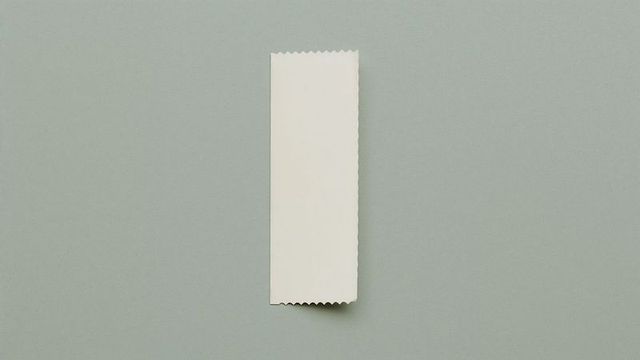 Blank ticket stub on grayish-green surface with zigzag edges