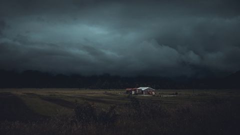 Solitary farmhouse under gloomy skies in rural landscape