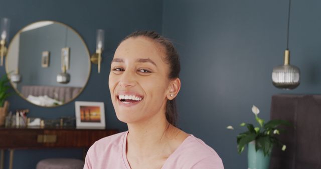 Image portrait of happy biracial woman smiling to camera in bedroom at home. Happiness, domestic life, and inclusivity concept.