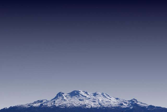 Mount Iztaccihuatl snowcapped peak is set against a clear blue sky, creating a serene and majestic view. Perfect for travel blogs, nature-themed presentations, advertisements showcasing outdoor gear, or inspiring desktop backgrounds.