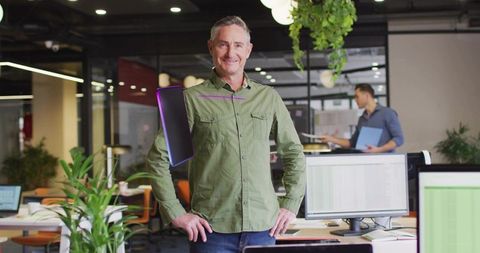 Smiling Man in Green Shirt Posing in Modern Open-Plan Office
