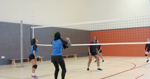 Diverse women's volleyball team practicing indoors wearing hijab emphasizing teamwork