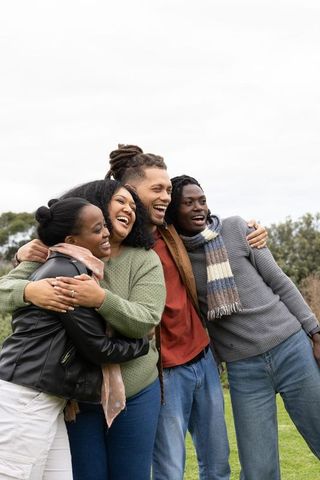 African American Friends Laughing and Hugging in Park Wearing Scarves and Jeans