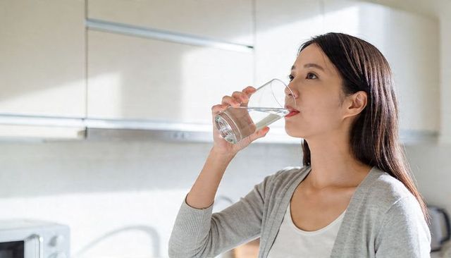 Woman drinking water in bright minimal kitchen for healthy hydration and morning routine
