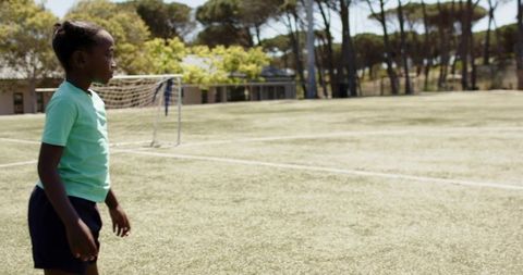 Young girl standing on soccer field near goal with wide copy space for sports branding