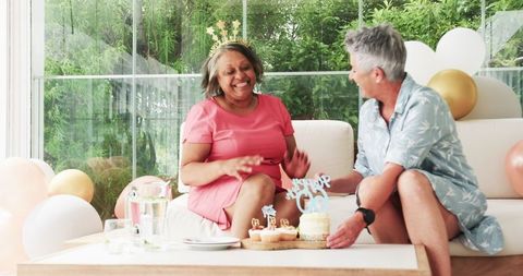 Joyful senior lesbian couple celebrates a birthday at home party