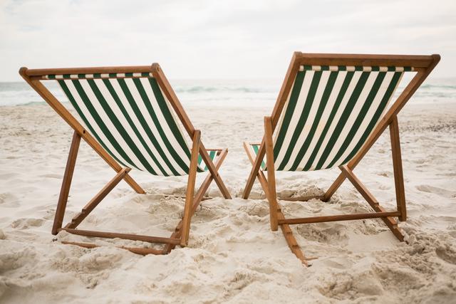 Two empty beach chairs on tropical sand beach