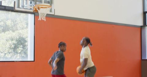 Indoor basketball training with asian coach and black players practicing rebound drills