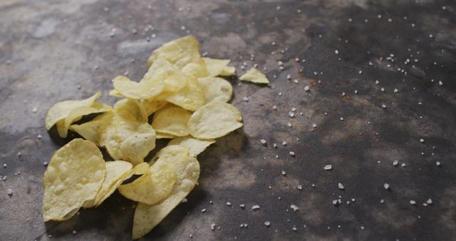 Close up view of salt falling over potato chips with copy space on black surface - Download Free Stock Photos Pikwizard.com