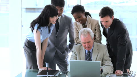 Diverse Team Collaborating Around Laptop in Bright Office Room
