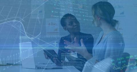 Colleagues discussing data analytics with laptop and tablet in modern boardroom