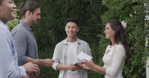 Friends celebrating outdoor wedding with tablet in hand