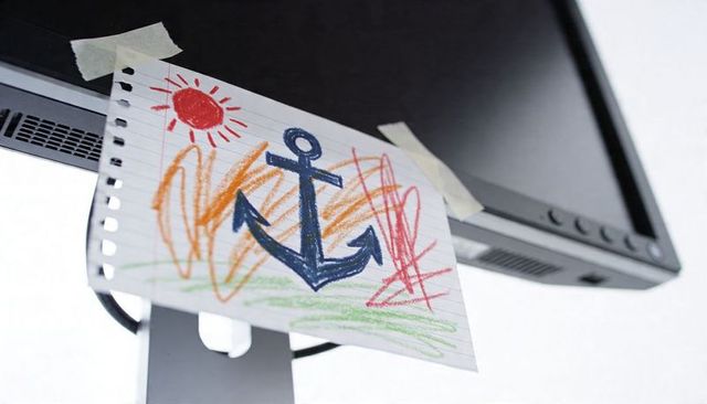 Torn notebook sheet taping to monitor with crayon anchor doodle and sun scribbles