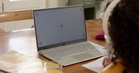 African american child studying with laptop and headphones at wooden table doing homework