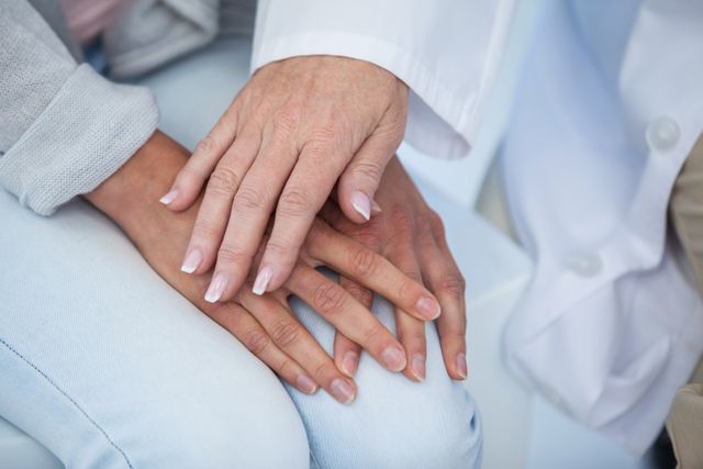 This image captures a close-up moment of a doctor providing emotional support to a patient by placing her hand on the patient's hand. Ideal for use in healthcare, medical, and wellness contexts to convey themes of empathy, support, and compassionate care.