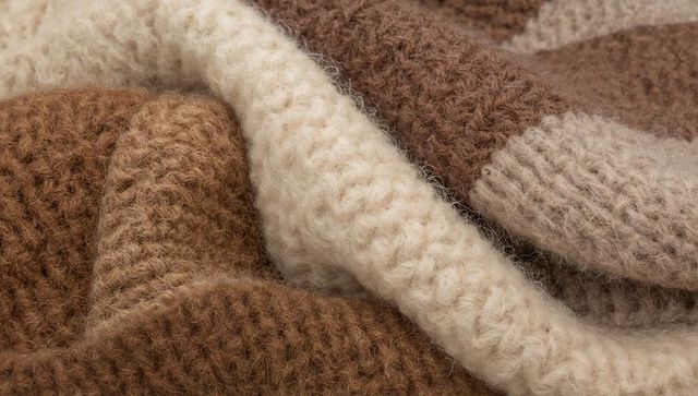 Chunky knitted wool closeup in warm neutrals showing soft fibers and cozy texture