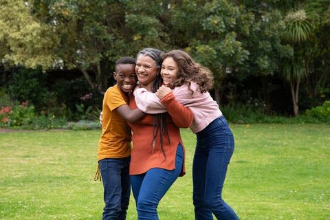 Loving Grandmother Hugging Teen Grandchildren in Lush Backyard
