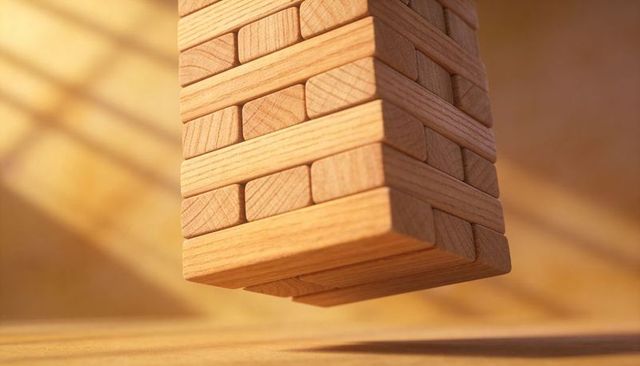 Hovering wooden block tower casting diagonal sunlit shadows conveying balance and risk