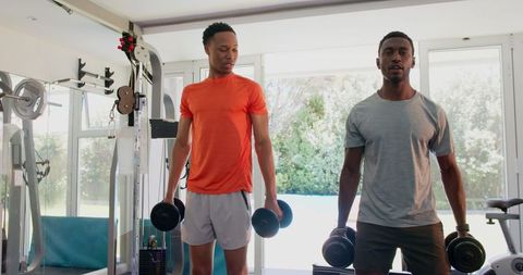 Men Lifting Dumbbells in Home Gym With Determined Focus on Fitness