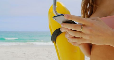 Young Woman Texting by Lifeguard Buoy on Sunny Beach