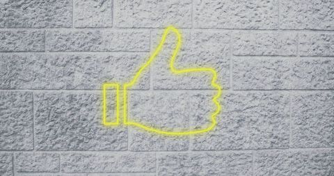 Neon thumbs up sign on brick wall background