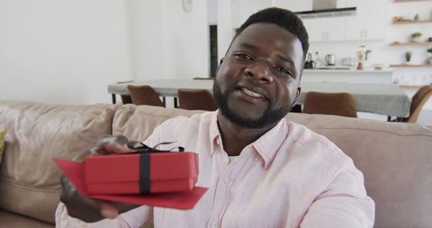 Man presenting gift box in virtual call at home