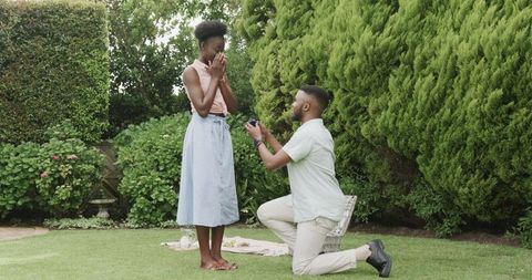 Surprised woman receiving romantic proposal in lush garden