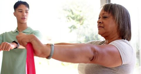 Senior Woman Using Resistance Band for Rehabilitation with Physiotherapist