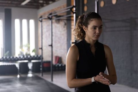 Focused woman preparing for workout in industrial gym wearing smartwatch and activewear