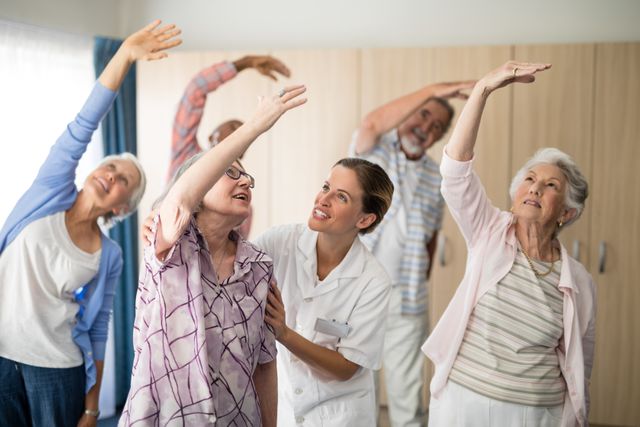 Smiling female doctor assisting senior woman exercising at retirement home