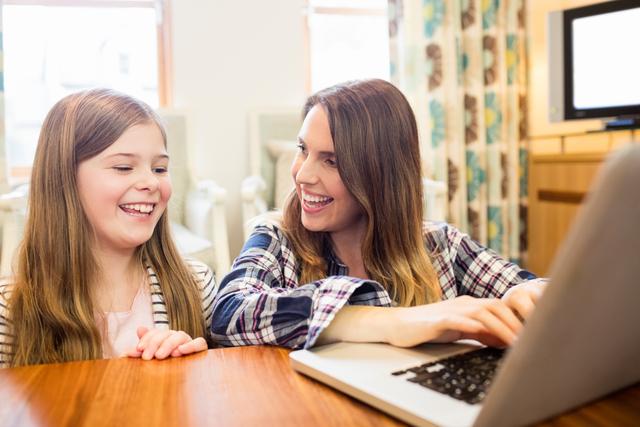 Mother and daughter using laptop in living room at home