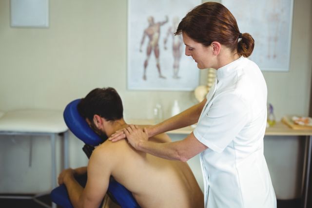 Physiotherapist giving back massage to a patient in the clinic