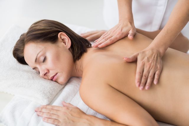 Naked woman receiving massage from masseur at spa