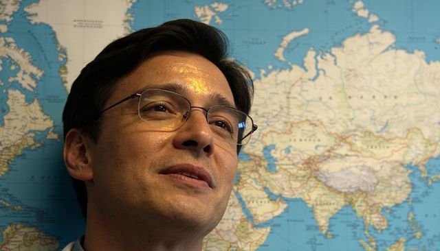 Gazing professional man studying world map wearing glasses and collared shirt for travel