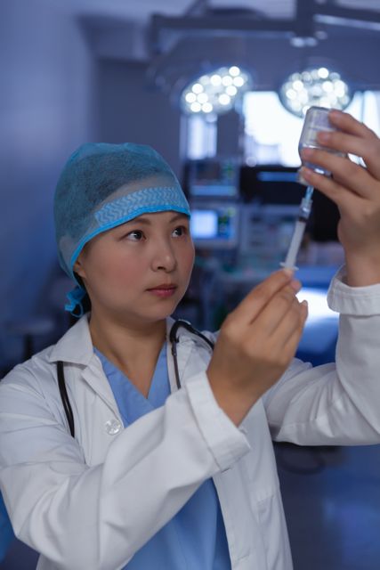 Female doctor in operating room preparing an injection from an ampule. Ideal for use in healthcare, medical, and hospital-related content. Can be used in articles, presentations, and educational materials about medical procedures, patient care, and the role of healthcare professionals.