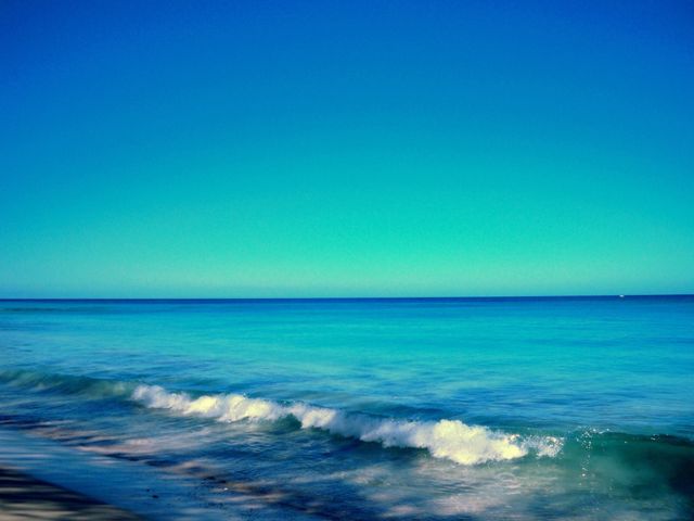 Tranquil Tropical Beach with Gentle Waves Under Clear Blue Sky - Download Free Stock Photos Pikwizard.com