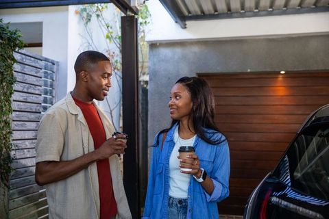 African American Couple Chatting by Parked Car with Coffee
