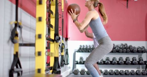 Fit Woman Performing Medicine Ball Toss in Gym