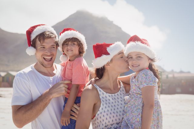 Family enjoying Christmas holiday at the beach, wearing Santa hats and smiling. Perfect for holiday greeting cards, travel advertisements, family vacation promotions, and festive season marketing materials.