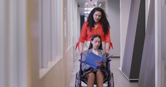 Businesswoman in Wheelchair Being Assisted by Colleague in Office Corridor - Download Free Stock Images Pikwizard.com