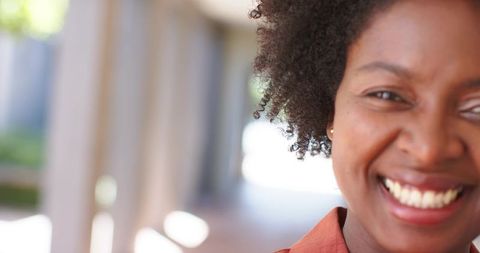 Smiling african american professional with afro wearing rust blazer, half-face headshot